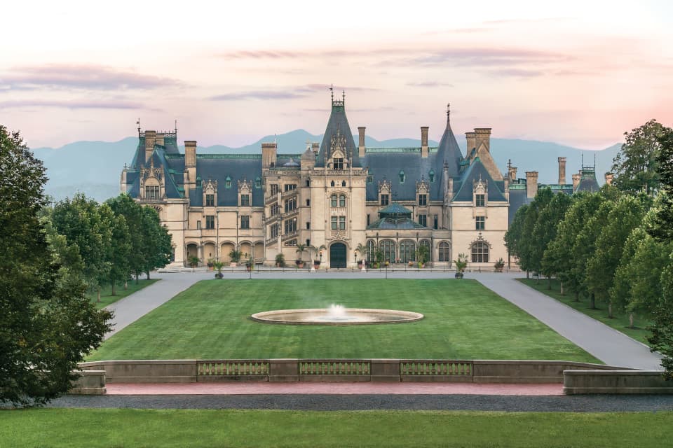 The iconic Biltmore House rises above its beautifully landscaped grounds with the Blue Ridge Mountains in the distance, showcasing one of Asheville's most celebrated landmarks and a must-visit destination during Biltmore Championship Asheville week. The iconic Biltmore House rises above its beautifully landscaped grounds with the Blue Ridge Mountains in the distance, showcasing one of Asheville's most celebrated landmarks and a must-visit destination during Biltmore Championship Asheville week.