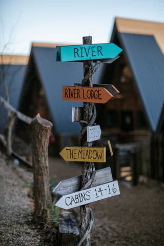 Directional sign at the Wrong Way River Lodge & Cabins showing the A-frame cabin row in the background. Directional sign at the Wrong Way River Lodge & Cabins showing the A-frame cabin row in the background.